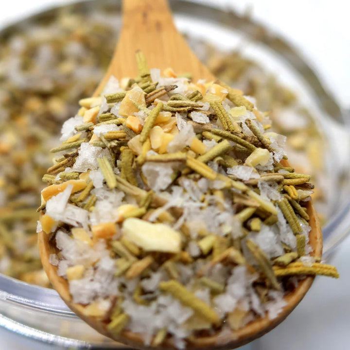 Wooden spoon filled with a mixture of herbs and spices over a blurred background