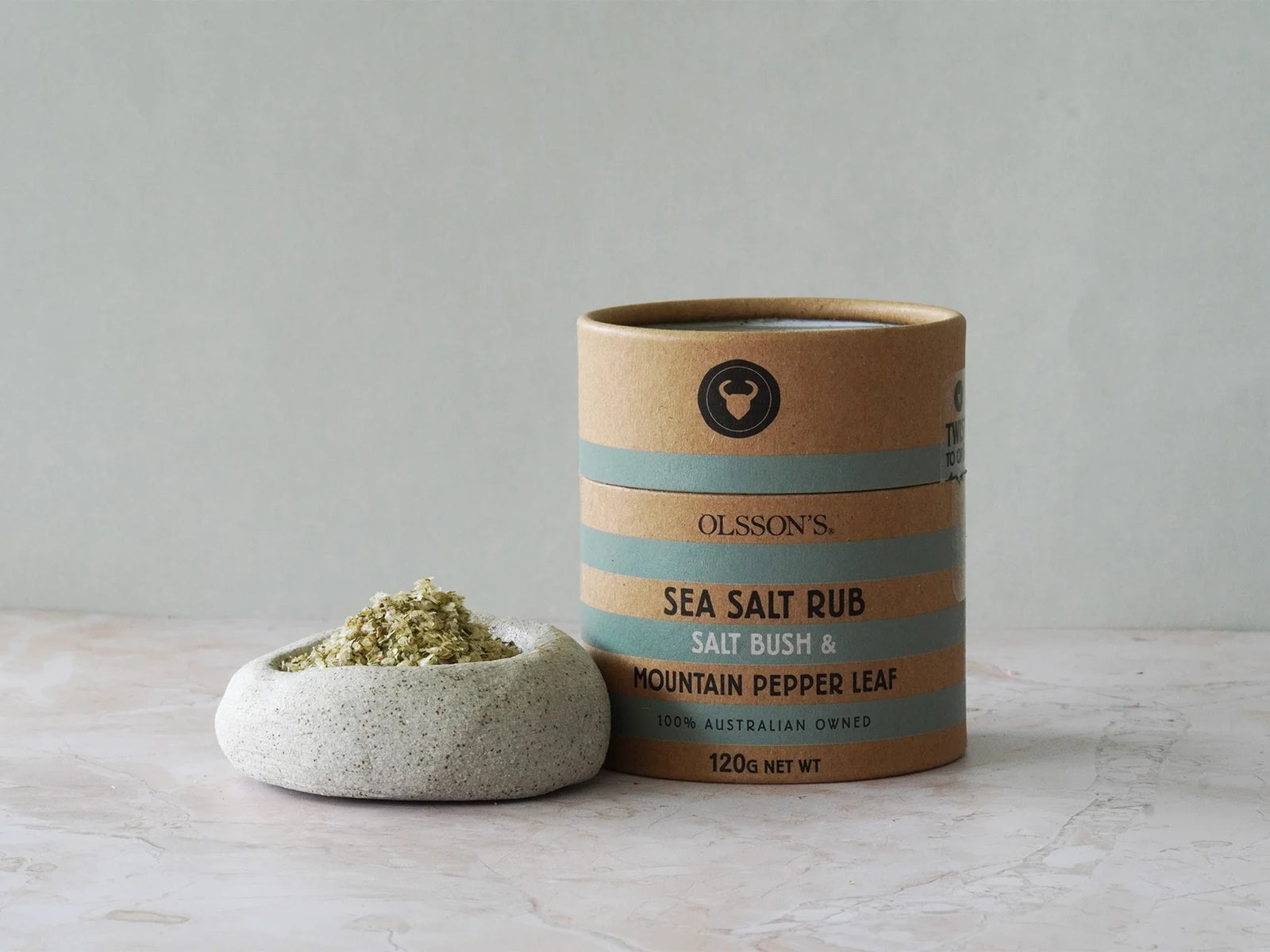 Olsson's Sea Salt Rub container with a small stone bowl of salt on a light surface.