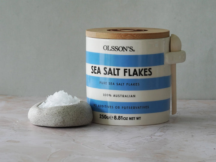 A stoneware jar of Olssons sea salt flakes with a ceramic container with salt in it