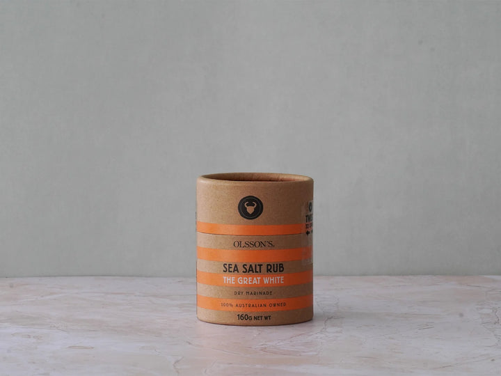 Cardboard container of sea salt rub on a wooden surface with a gray background