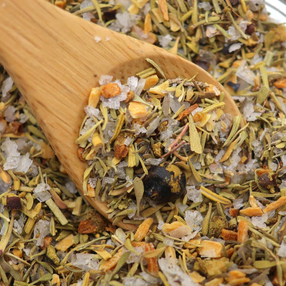 Wooden spoon filled with a mix of dried herbs and spices on a bed of similar herbs.
