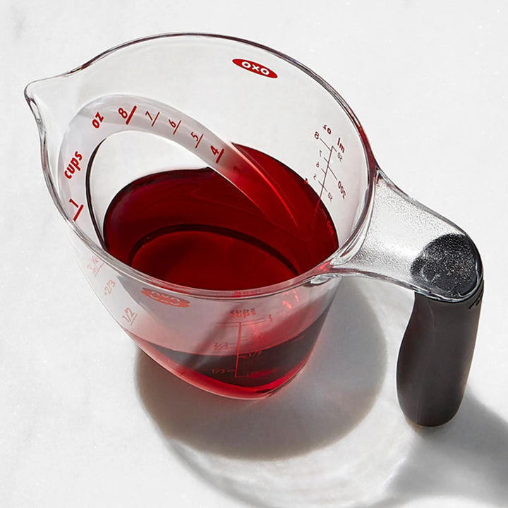 Clear measuring cup with red liquid on a white background