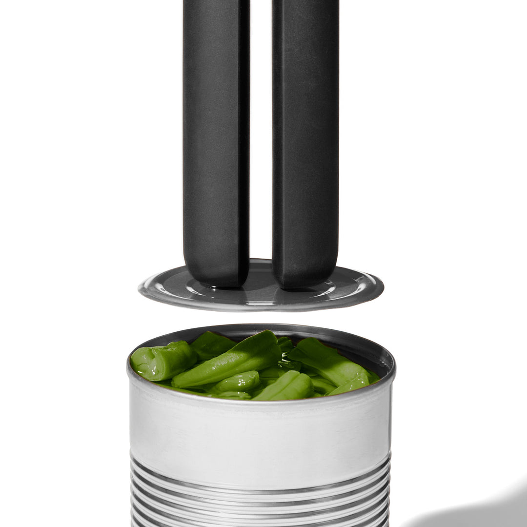 Metal can opener with a can of green beans on a white background