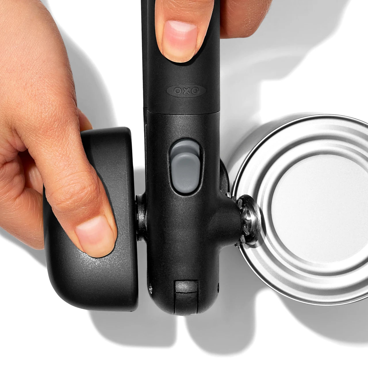 Hand using a can opener on a white background