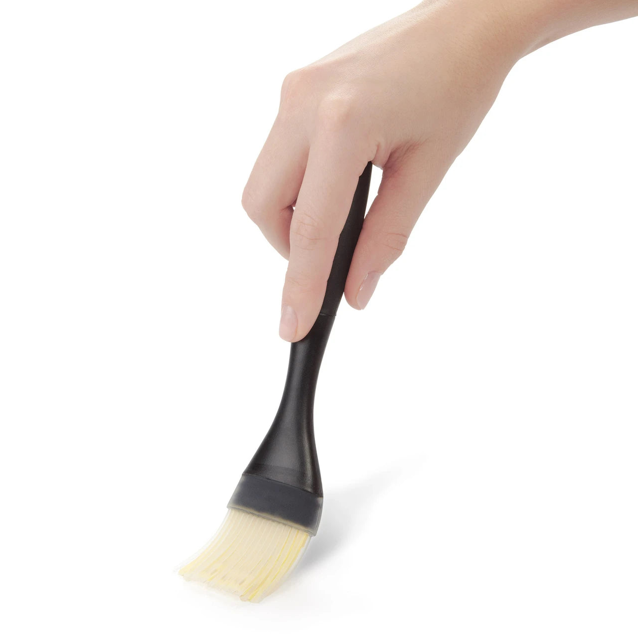 Hand holding a black and beige brush against a white background