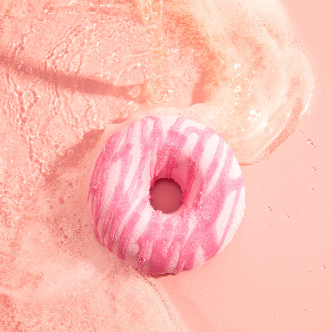 Pink and white striped donut-shaped bath bomb on a pink background