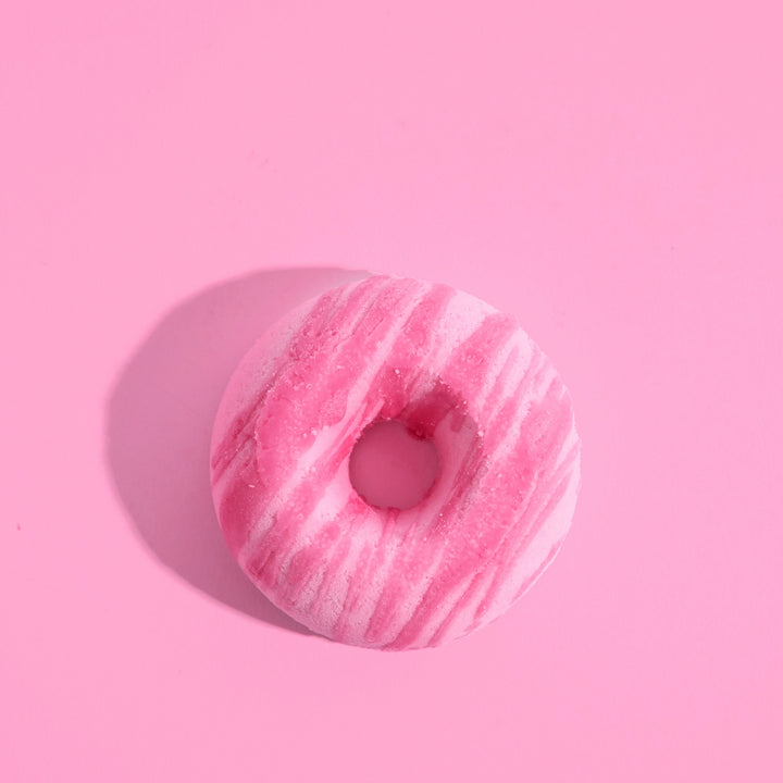 Pink donut-shaped bath bomb on a pink background