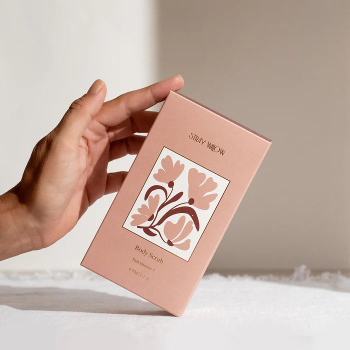 A hand touching a box of Stray Willow body scrub
