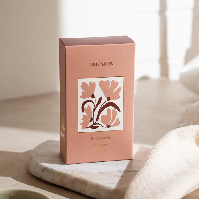 Pink body scrub box with floral design on a marble surface