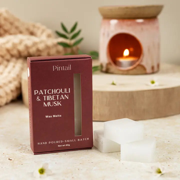 Pintail Patchouli &amp; Tibetan Musk wax melts packaging with a candle in the background