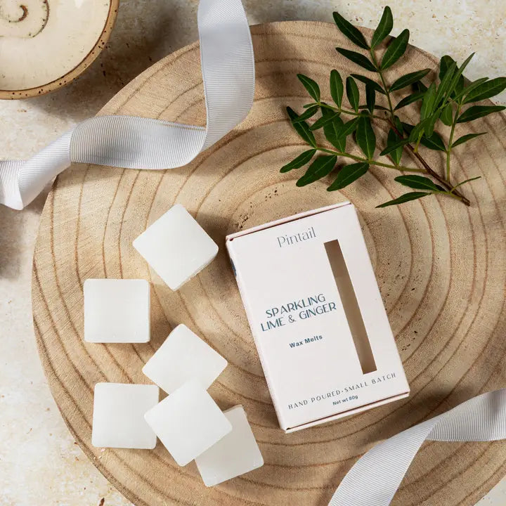 Wax melts and packaging on a wooden surface with greenery