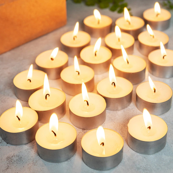 Multiple lit tealight candles on a flat surface with a blurred background