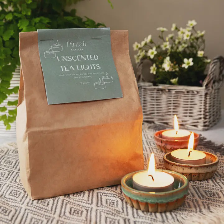 Pintail unscented tea lights packaging with lit tea lights on a patterned surface.
