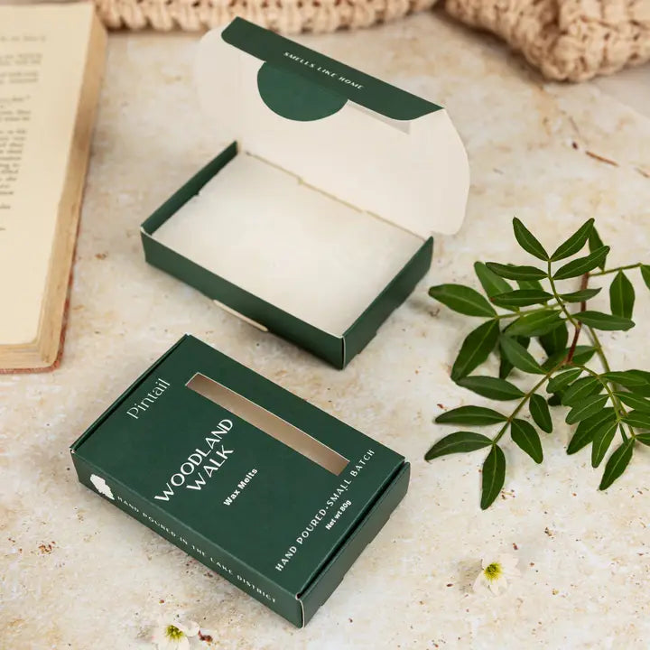 A box of wax melts on a textured surface with plants