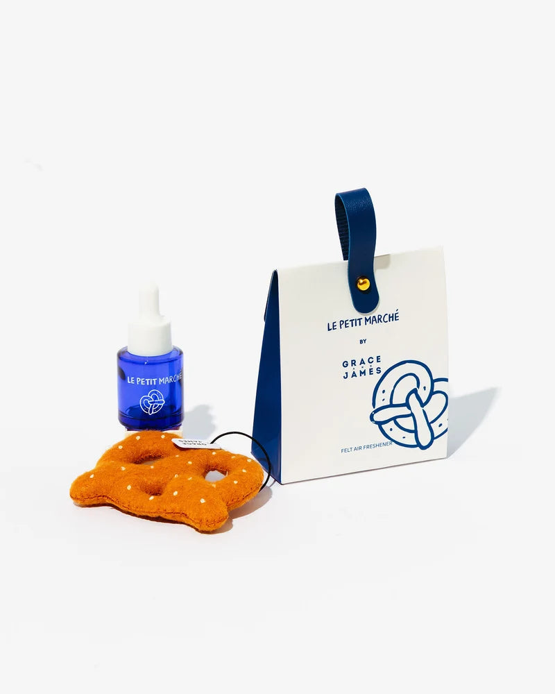 A box and felt pretzel air freshener with a blue bottle of fragrance