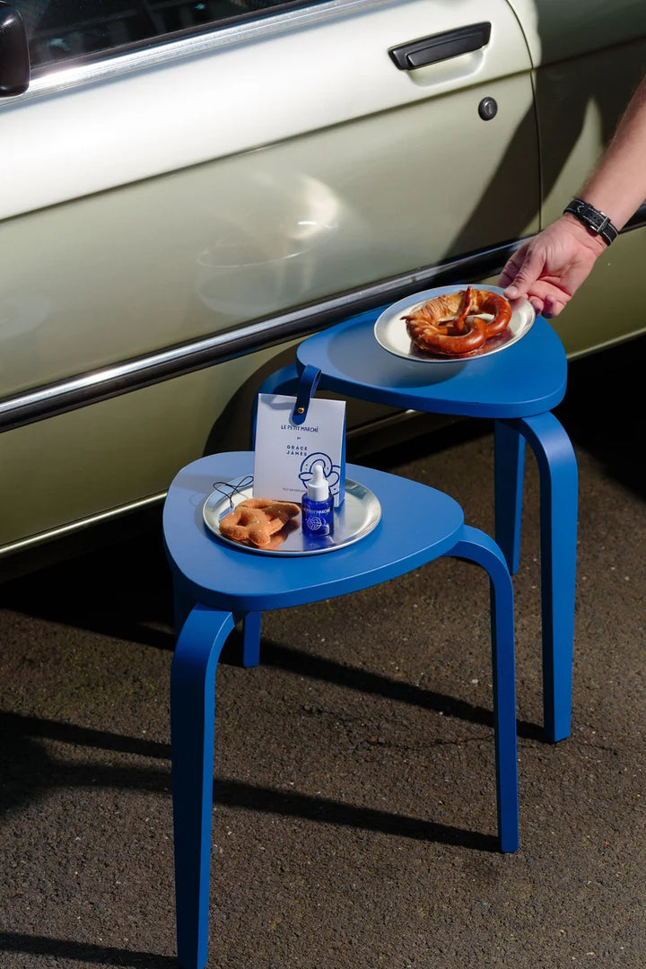 Two blue stools with a box and felt pretzel air freshener with a blue bottle of fragrance