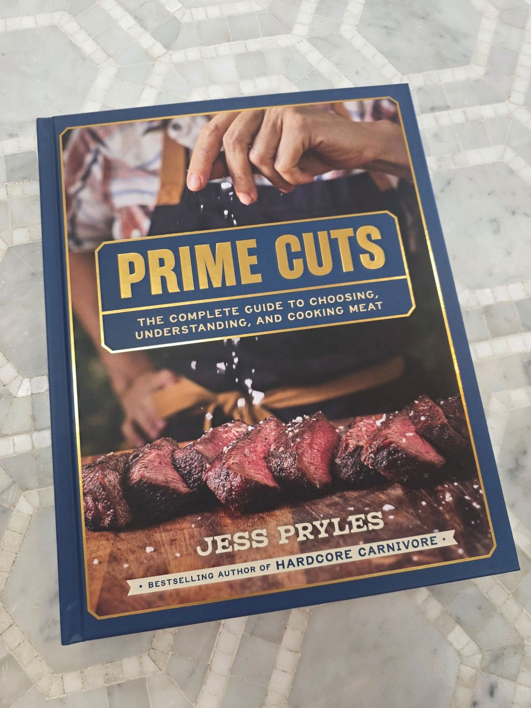 Prime Cuts Cookbook on a tiled marble background