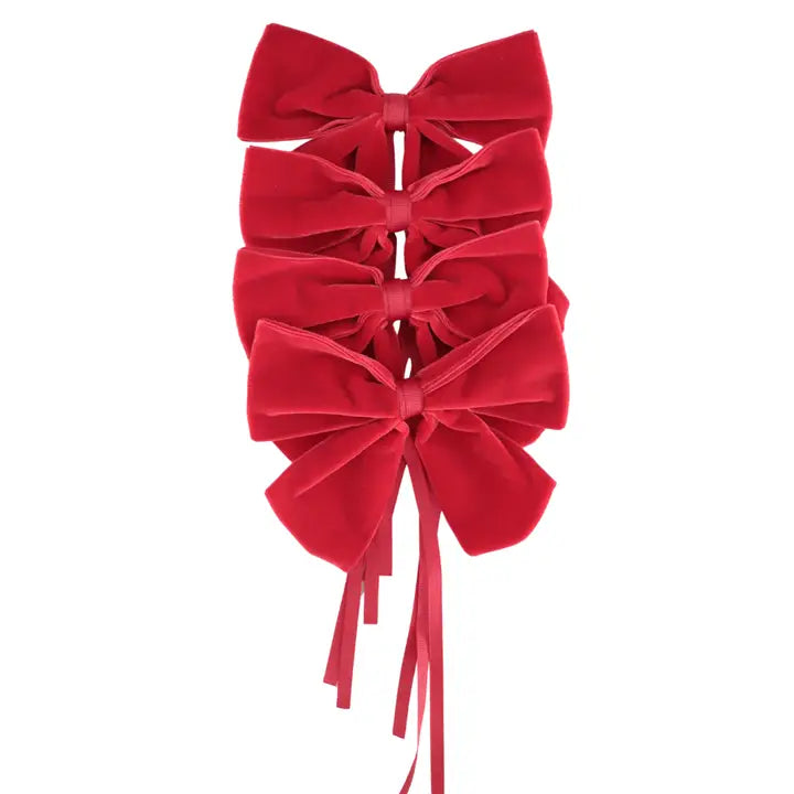 Three red velvet bow napkin holders with long ribbon tails, stacked vertically on a plain white background.