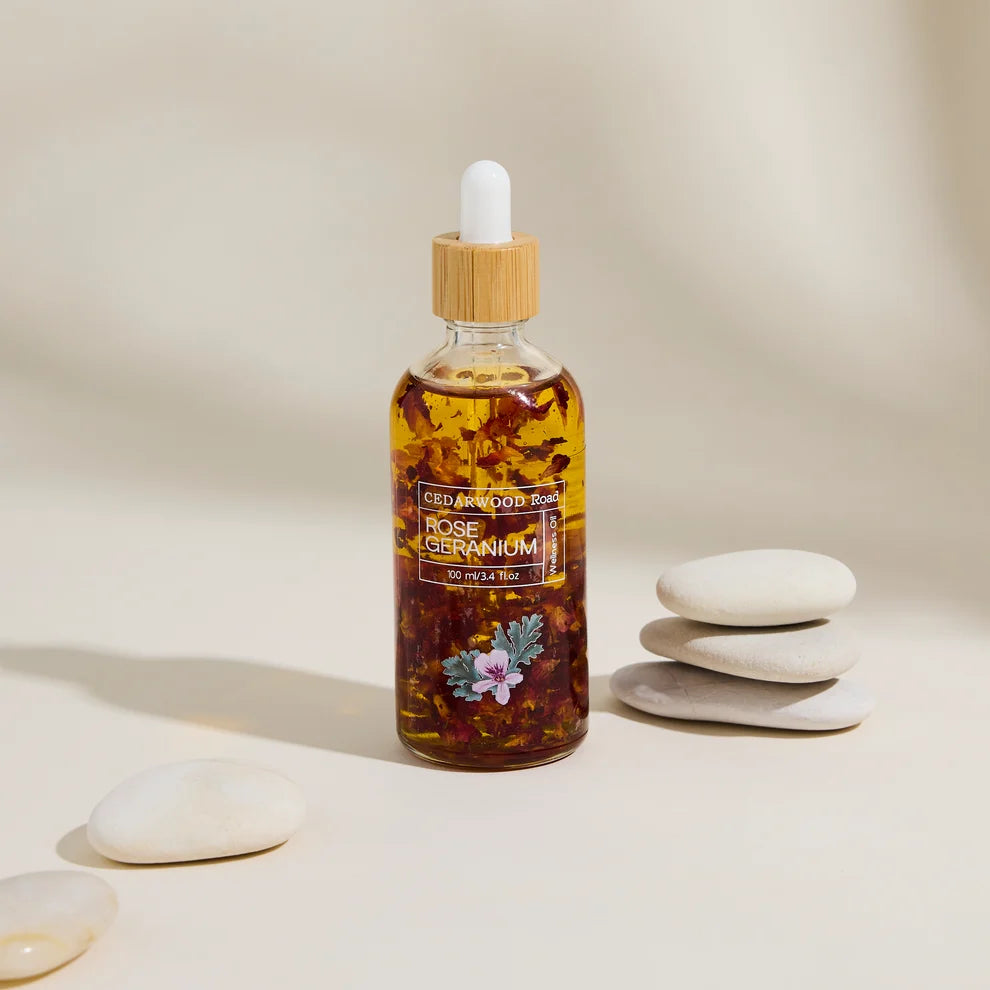 A bottle of Cedarwood Road Rose Geranium wellness body oil on a beige background