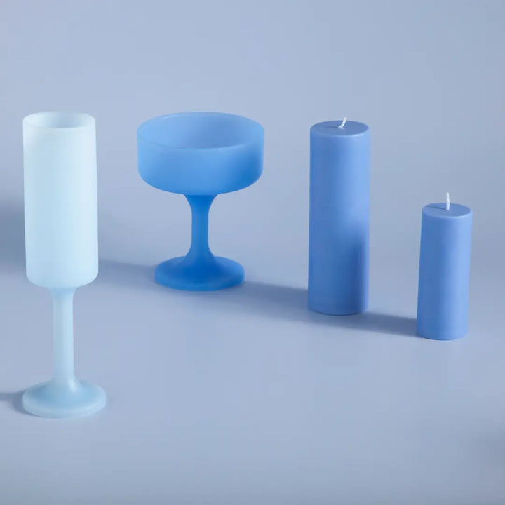 Set of blue silicone wine glasses and candles on a light gray background