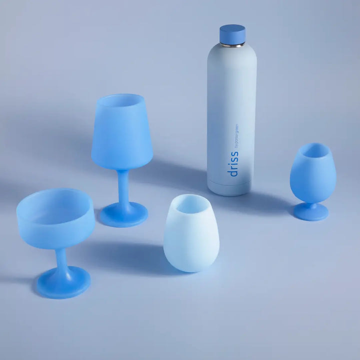 A set of blue and white travel drinkware, including a tall insulated bottle and four matching silicone cups in shades of light and medium blue, arranged on a light blue-gray background.
