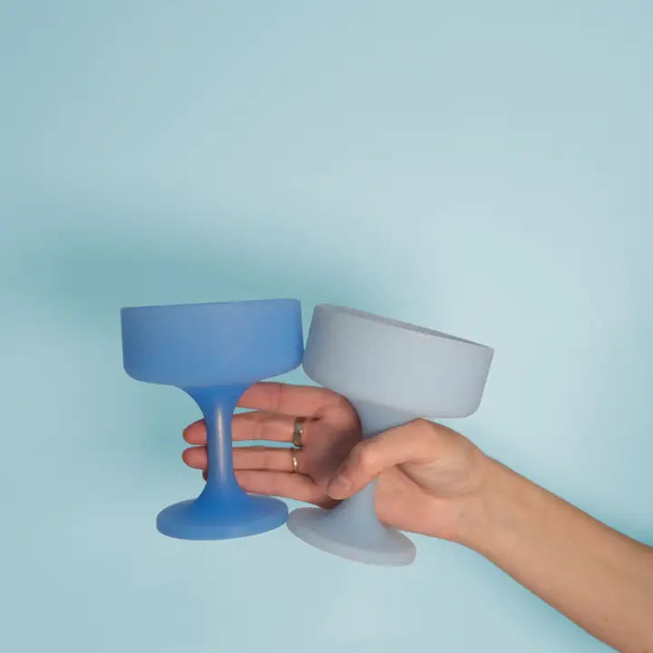Two silicone cocktail glasses in blue and light gray, held by a person&
