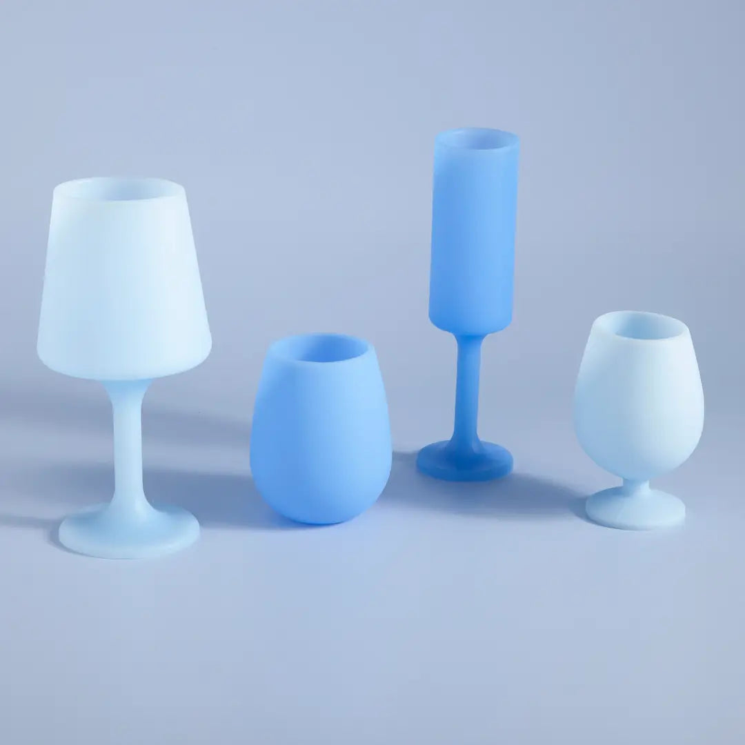 Four matte blue and white molded drinking glasses or candle holders arranged on a light gray studio background.