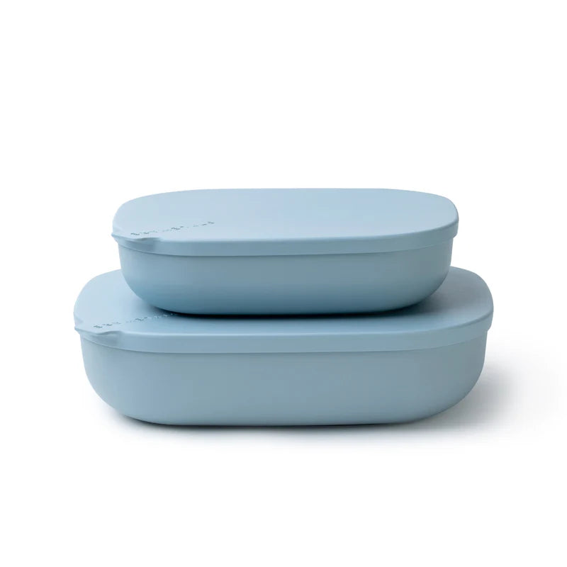 Two light blue silicone lunch containers with matching lids, stacked on a clean white background.