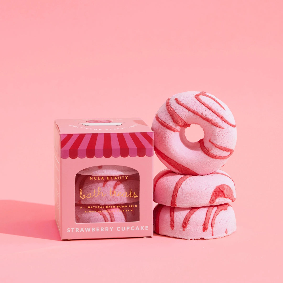 Pink bath bomb trio with a striped box on a pink background