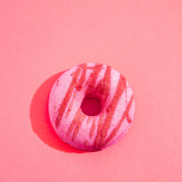 Pink donut-shaped bath bomb on a pink background