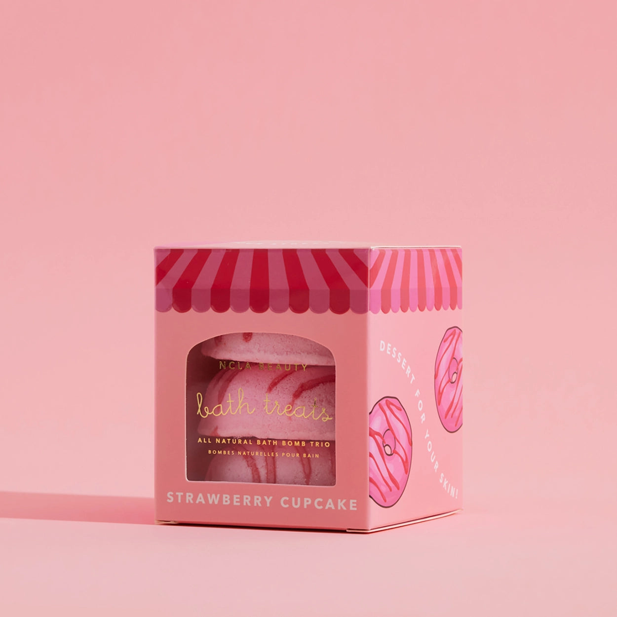 Pink packaging of bath bombs with a strawberry cupcake theme on a pink background