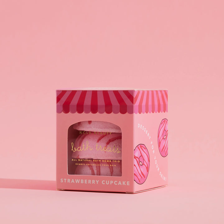 Pink packaging of bath bombs with a strawberry cupcake theme on a pink background
