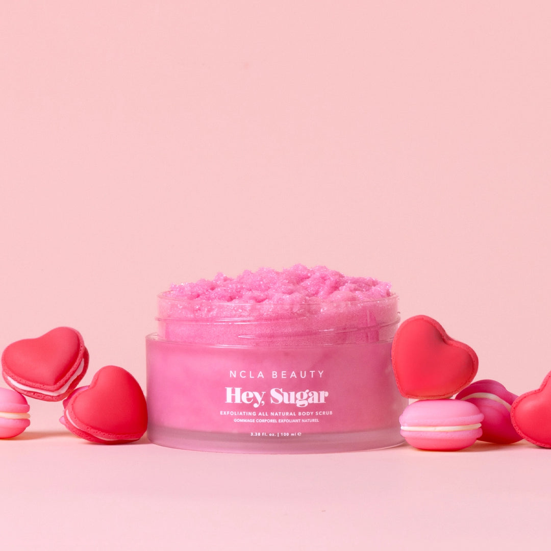 Pink body scrub jar with heart-shaped containers on a pink background