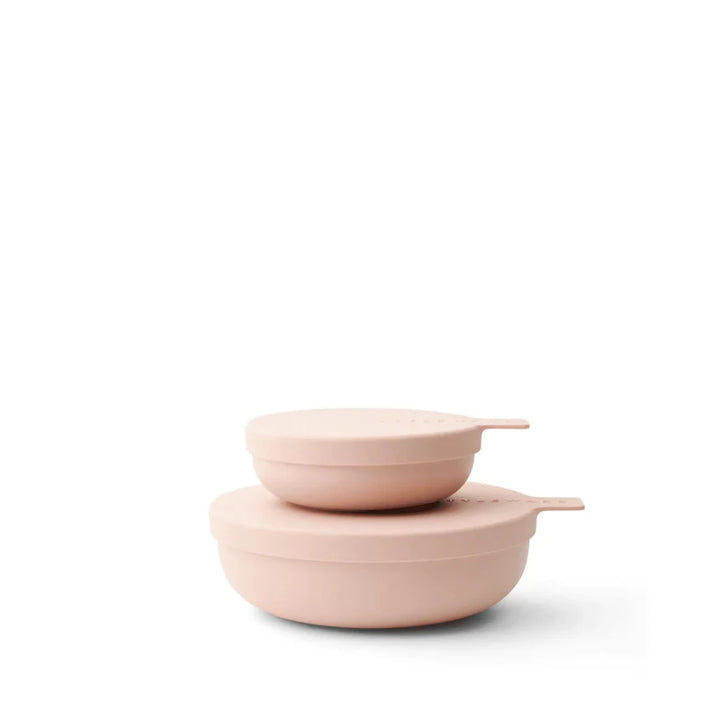 Two blush plastic storage bowls stacked on a white background