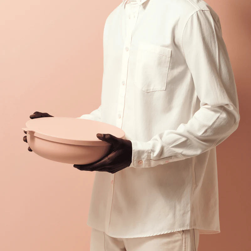 Person holding a blush storage bowl against a peach background