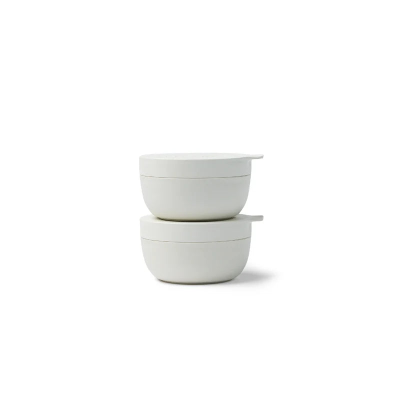 Two stacked white ceramic bowls with matching lids, photographed on a clean white background.