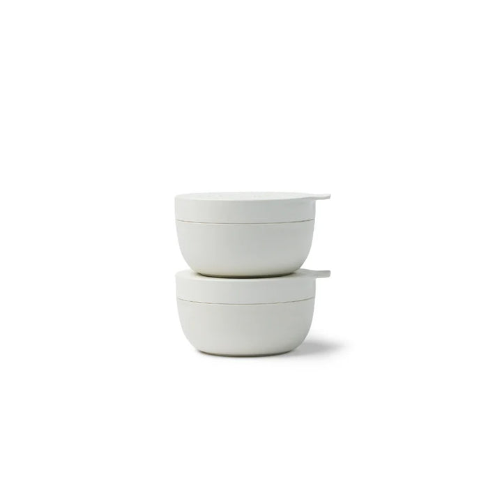 Two stacked white ceramic bowls with matching lids, photographed on a clean white background.