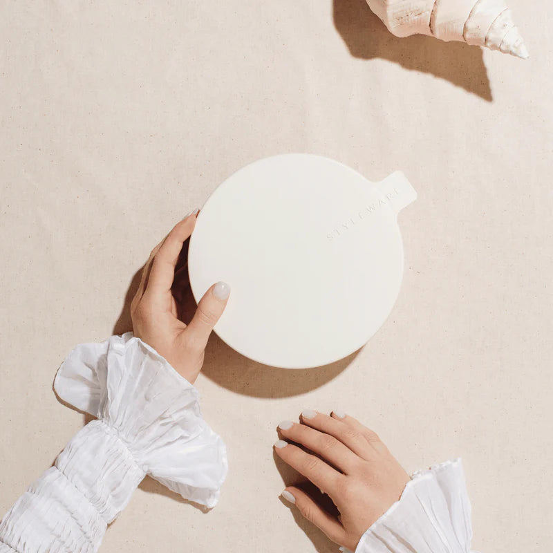 Person holding a white plastic bowl with lid on a beige surface
