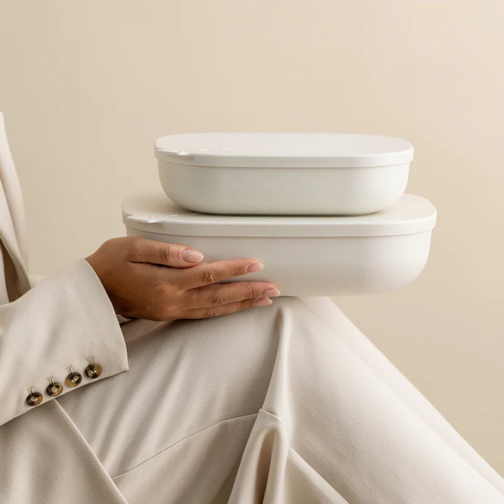 Two matte white oval storage containers with lids, stacked on a person&