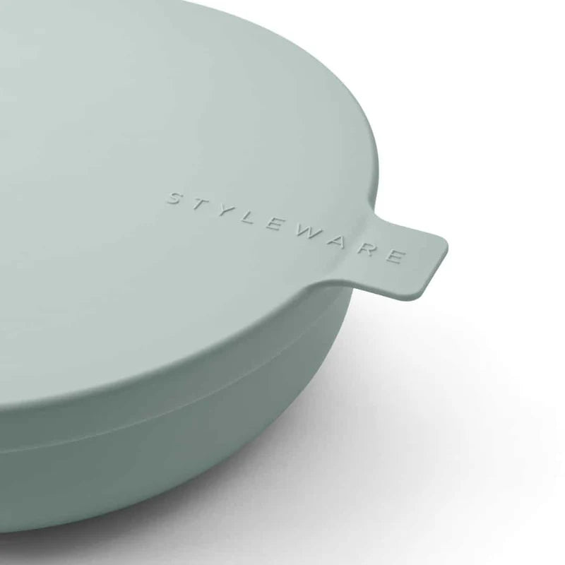 Light green bowl with lid on a white background, featuring &