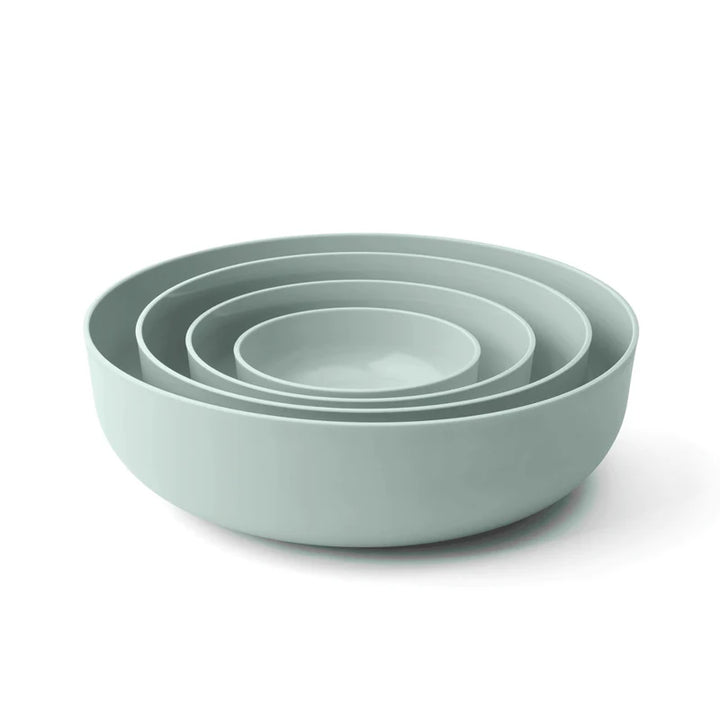 Set of four light sage bowls of different sizes on a white background
