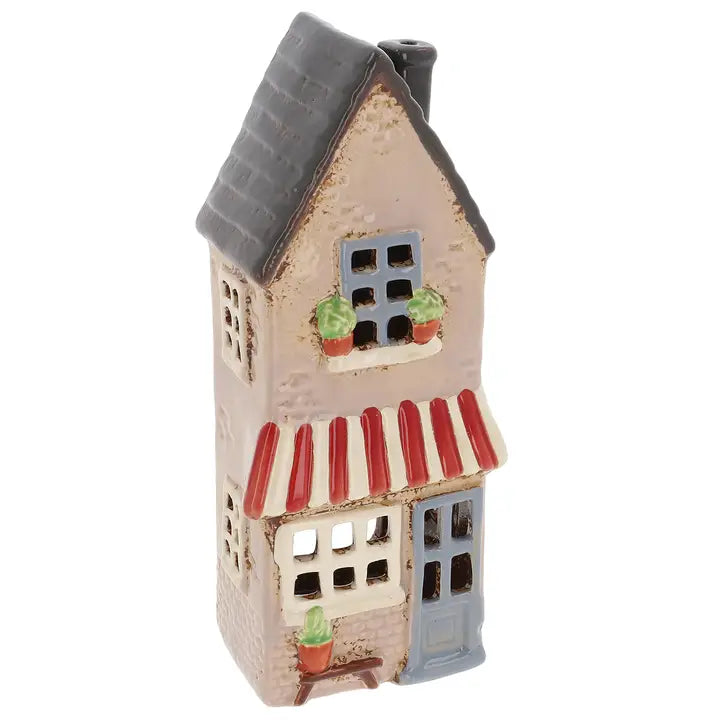 Tall ceramic house tealight holder with a gray roof and red striped awning on a white background
