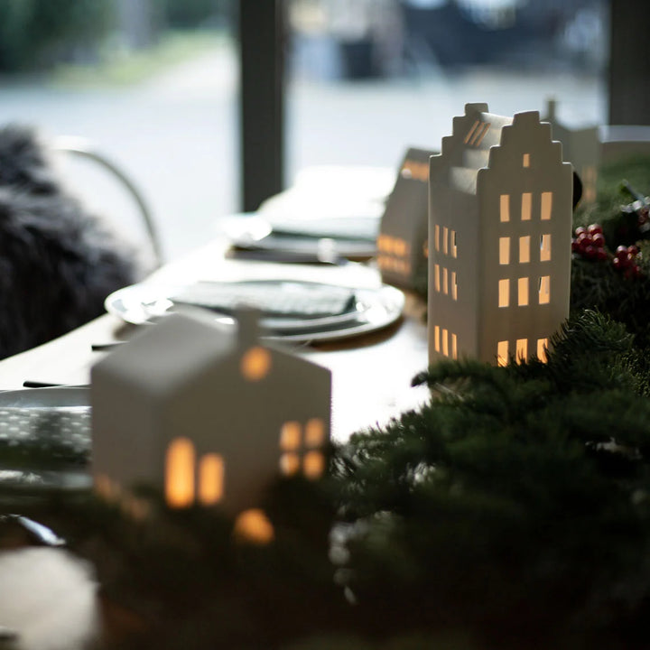 Styled table with white ceramic tealight house candle holders with lit candles