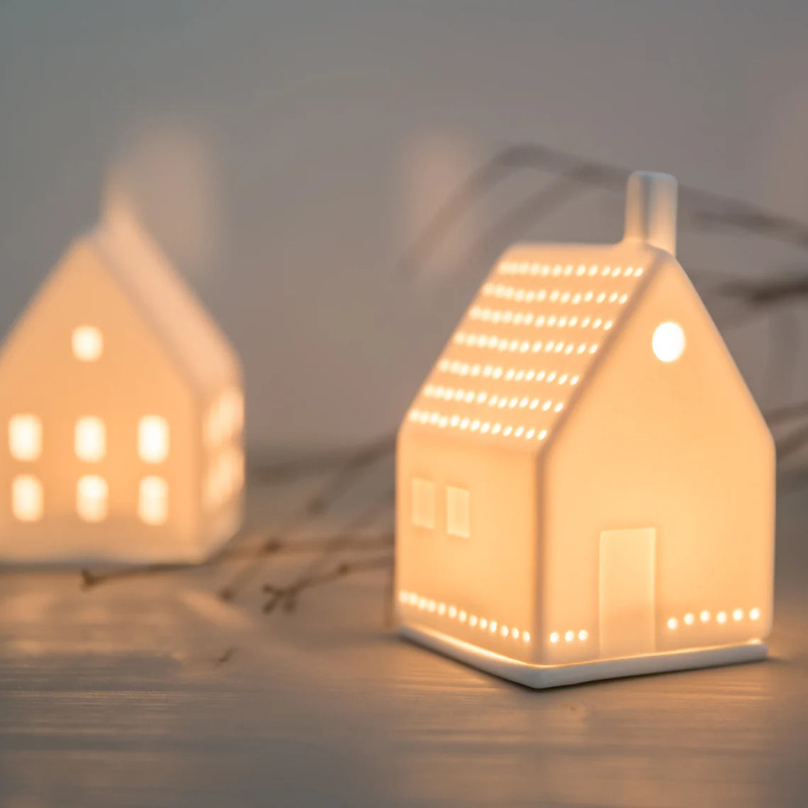 White ceramic tealight house candle holder with lit candle inside