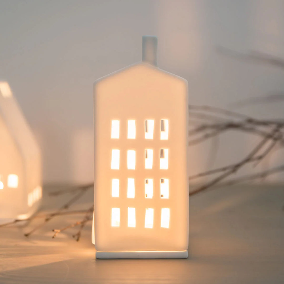 White tealight house candle holder with rectangle windows with a lit candle inside