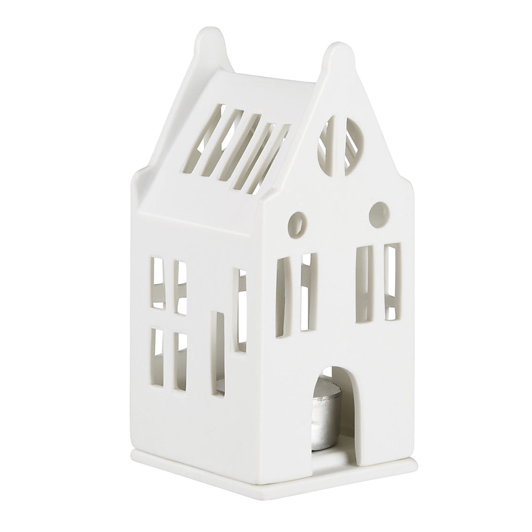 A white ceramic house-shaped candle holder with cutout windows and a small tealight candle visible inside, set against a plain white background.