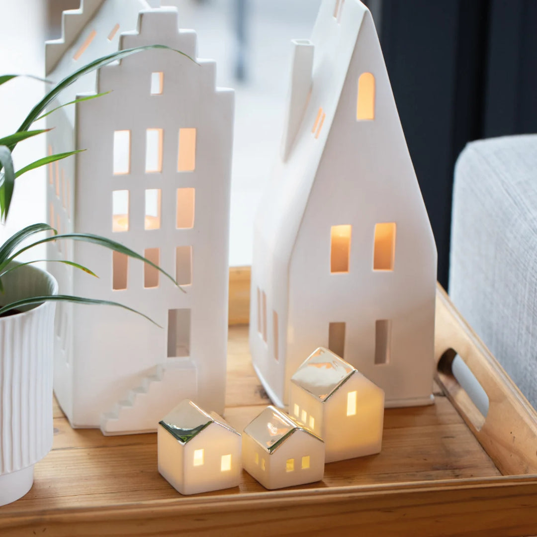 Set of white porcelain tealight house candle holders on a wood serving tray