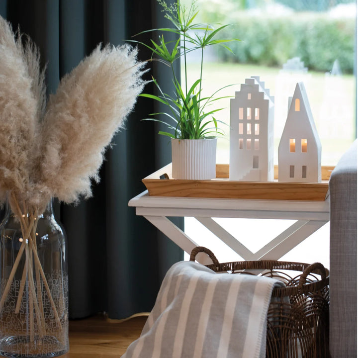 White porcelain tealight house candle holders on a side table in front of a window