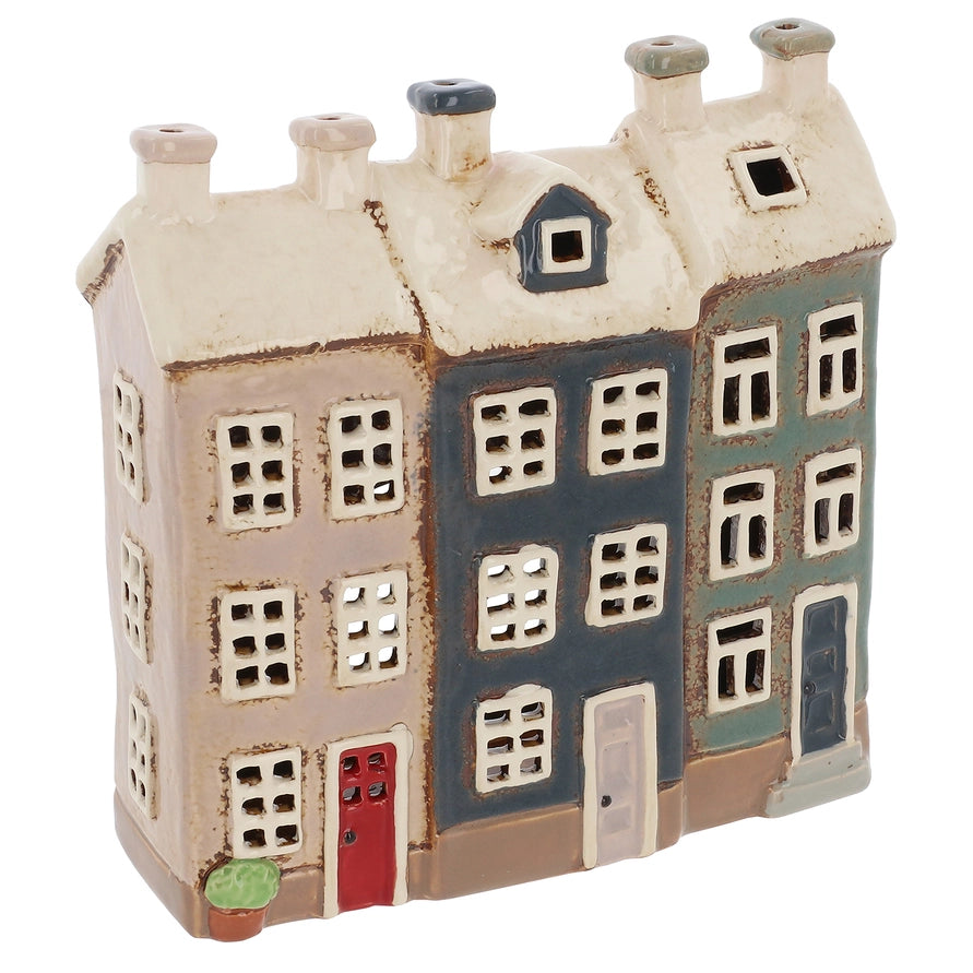 Ceramic tealight holder of a multi-story building with different colored sections on a white background