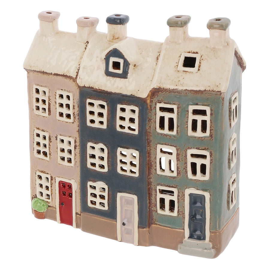 Ceramic tealight holder of a multi-story building with different colored sections on a white background